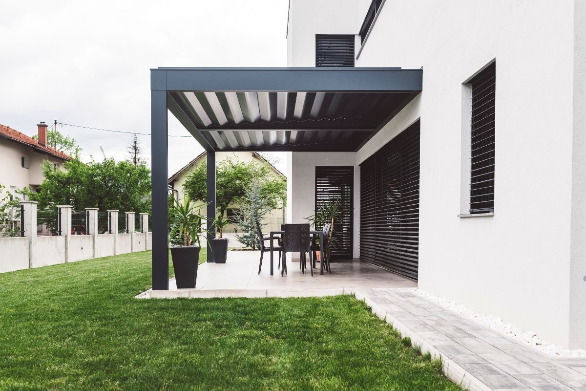 A patio featuring a white roof, palm trees, and furniture service, creating a tropical and inviting outdoor space.